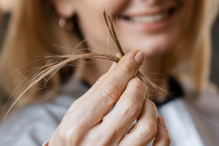 Frau hält ein Bündel Haarspitzen zwischen den Fingern